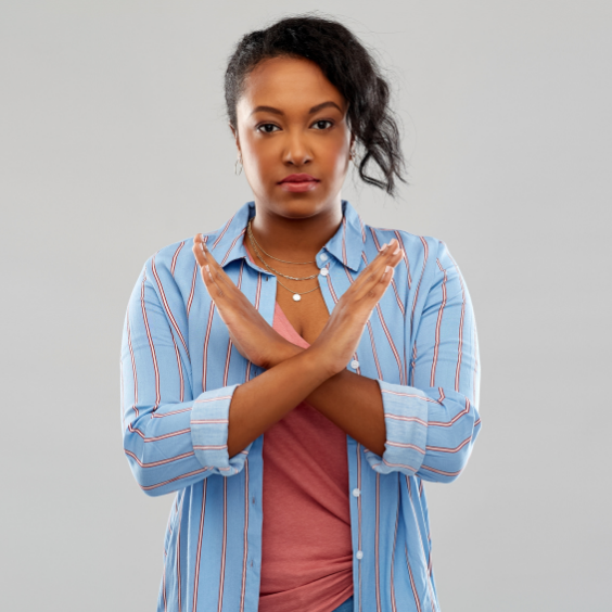 A woman in a pink t-shirt and blue button down shirt making an X with her hands and forearms.