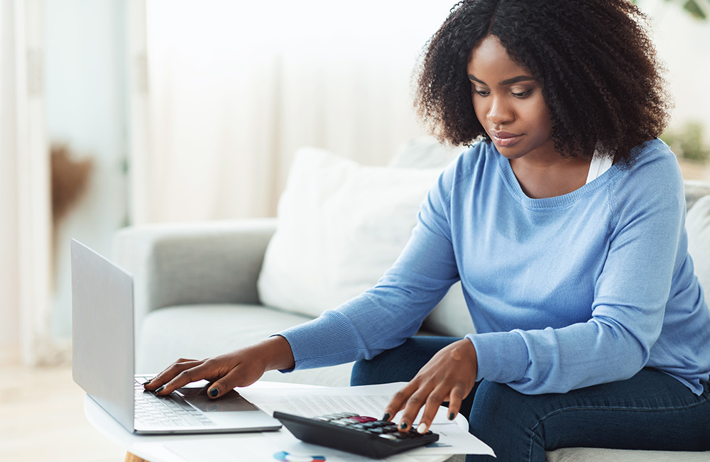 Business Accounting. African Businesswoman Using Calculator And Working With Laptop. Copy Space