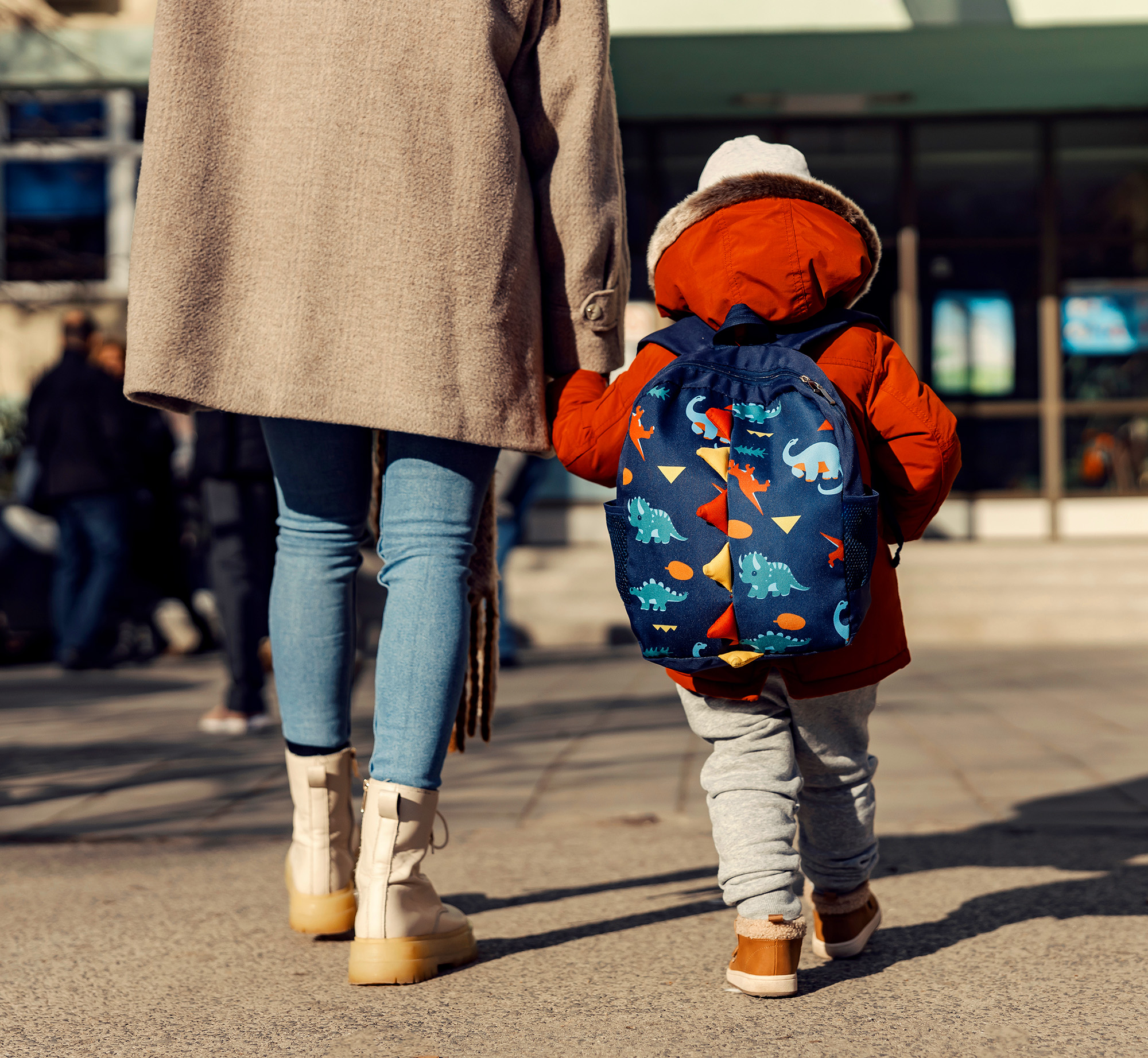 A mother entering the kindergarten yard with her preschooler boy.