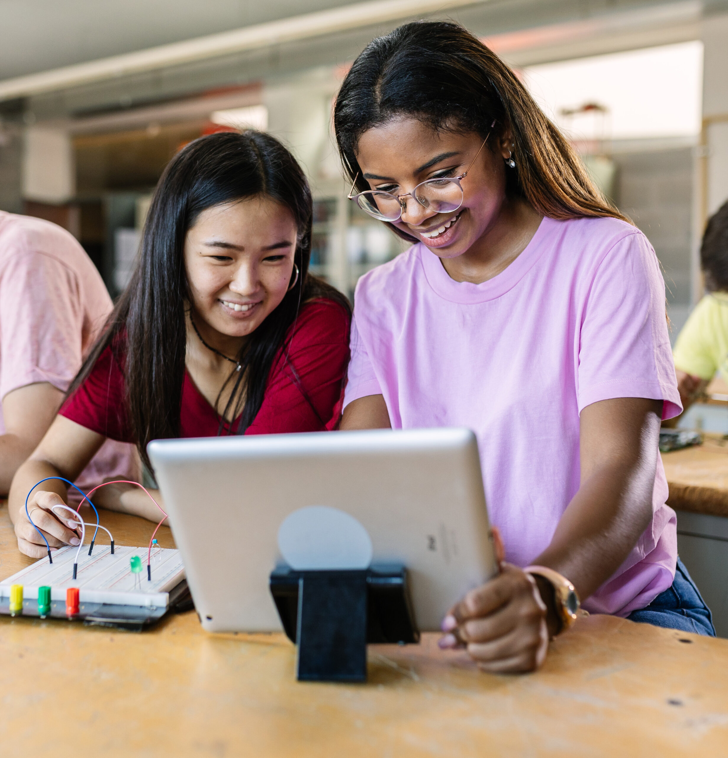 Group of diverse teenage students learning together to build electronic circuits at high school - Asian and african american female classmate working at technology class